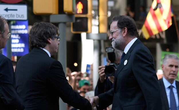 Mariano Rajoy (d.) saluda a Carles Puigdemont (i.). / AFP