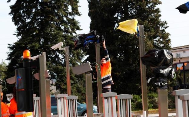 Operarios quitan las bolsas en las cámaras del peaje de la Ap-7 a la altura de La Roca del Vallès./Alejandro García (Efe)