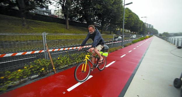 Paseo y carril bici. Pese a la lluvia, la pasarela recibió ayer a los primeros usuarios. /  F. DE LA HERA
