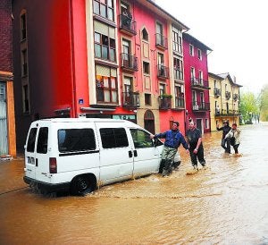 Vecinos de Villabona auxilian a un conductor en una calle anegada. :: KARLIS/