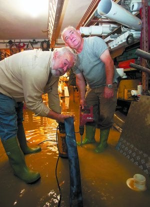 Dos personas achican agua en un almacén inundado de Martutene. ::
MICHELENA/