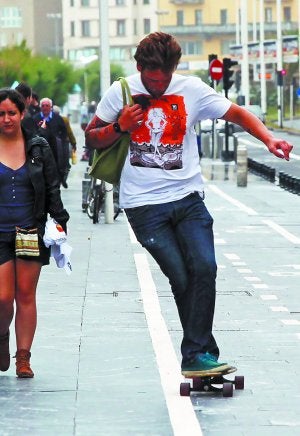 Pista multiusos. Un joven se desplaza en patinete por el carril bici que recorre el paseo de La Zurriola. :: FOTOS: NAGORE IRAOLA/