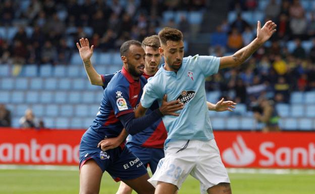 Brais Méndez protege el balón ante dos jugadores del Huesca, durante un encuentro en Balaídos. 