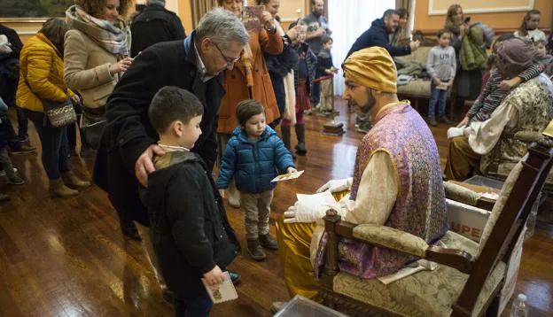 Días de emociones. Dos niños entregan sus cartas al paje del rey Melchor, ayer en la sala Capitular del Ayuntamiento. / FOTOS F. DE LA HERA