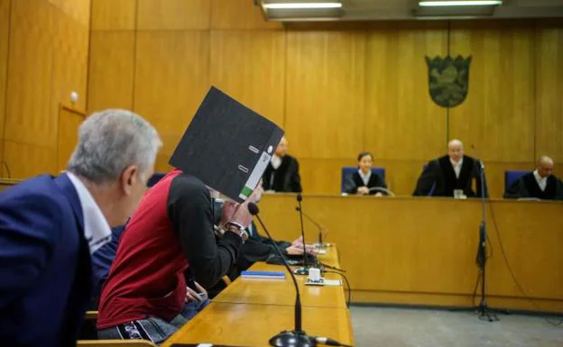 The condemned man, Taha al J .. hides his face behind a folder during the trial.