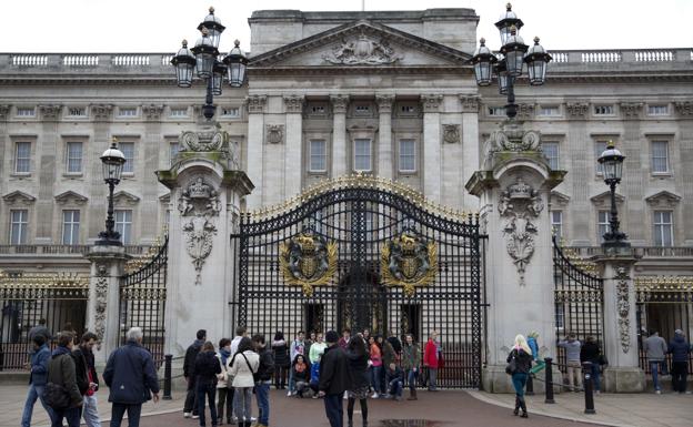 Tourists are photographed on the gates of Buckingham Palace.