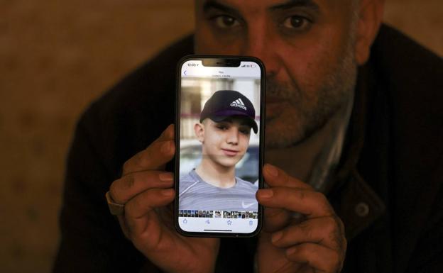 Amal's father with a photo of his son on his mobile phone.