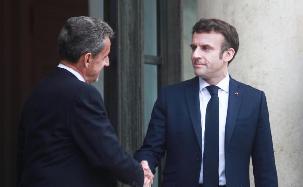French President Emmanuel Macron greets former French President Nicolas Sarkozy.