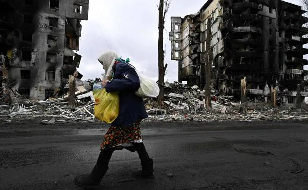 A woman walks through the streets of the city of Borodianka, with the houses destroyed.