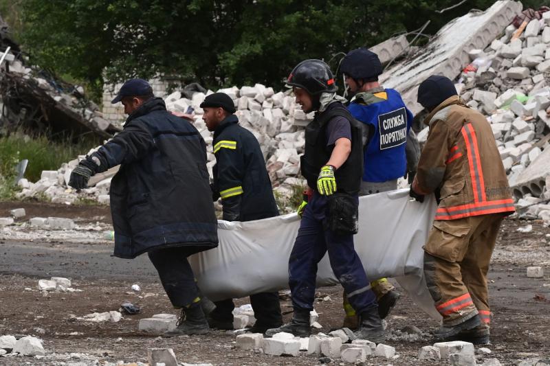 Rescue teams move the body of a neighbor from the attacked building in Chasiv Yar 