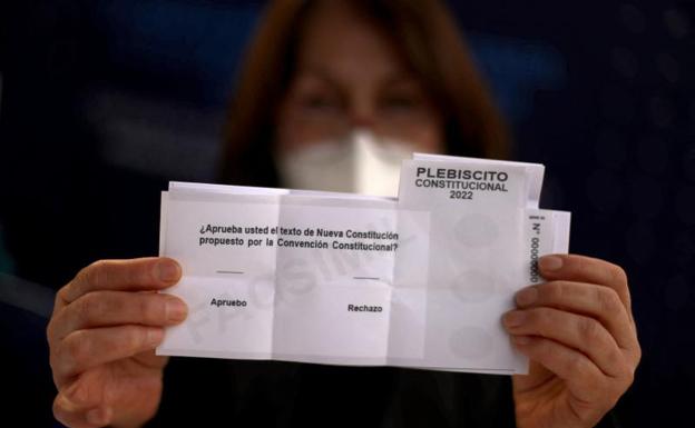 An employee of a polling station shows a ballot paper. 