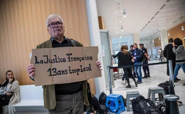 Winfried Schmidt, relative of one of the victims, at the entrance of the courts with a sign that reads 'French Justice 13 years too late', this Monday in Paris.