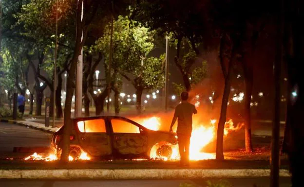 An individual watches a burning vehicle in Brasilia. 