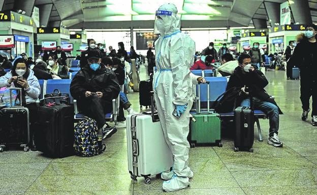 A passenger waits for his flight at the Beijing airport dressed in a security suit.