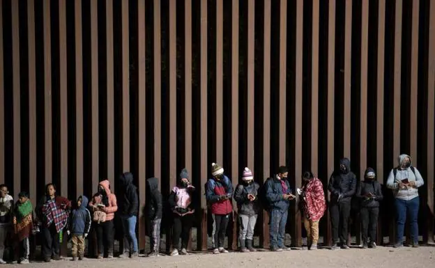 Asylum seekers queue to be processed by US Customs and Border Patrol agents at a breach in the border fence with Mexico near Somerton, Arizona.